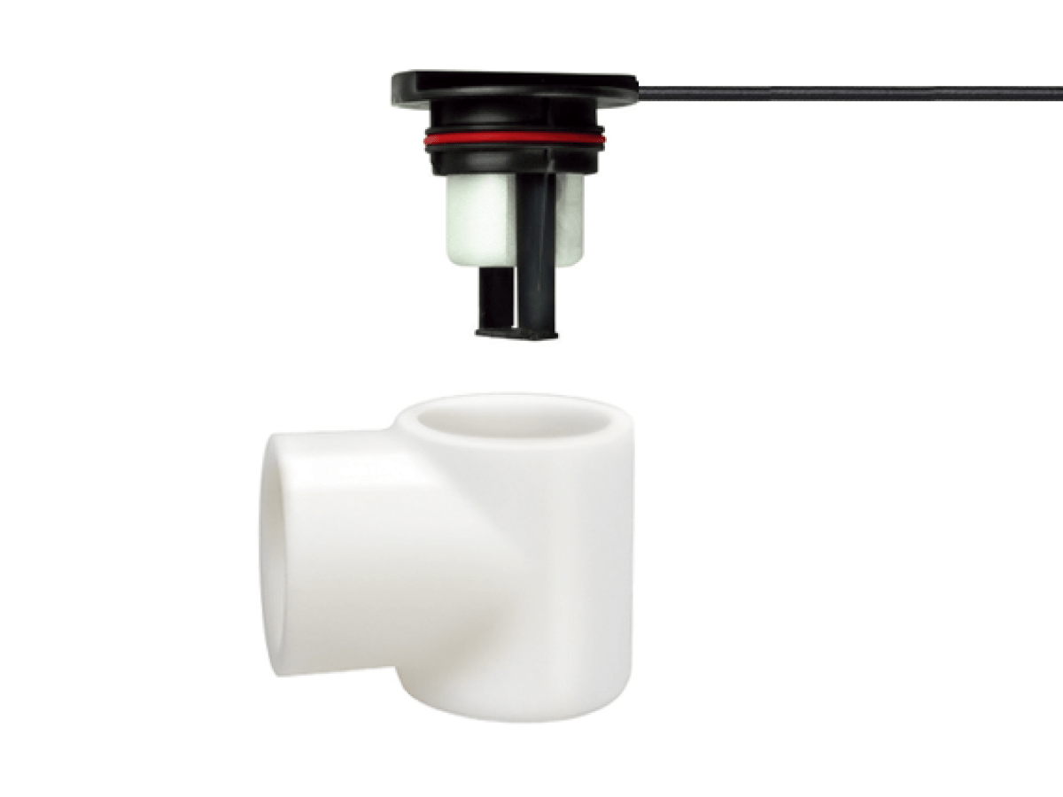 A black and white FPS-L Series electronic liquid level sensor with a wire is positioned above a white plastic T-shaped pipe fitting, commonly used in HVAC systems, isolated on a white background. by Standex Detect