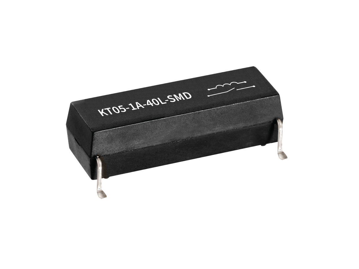 A black rectangular KT Series Reed Relay electronic component with metal pins on each end, labeled KT05-1A-40L-SMD and a schematic symbol, isolated on a white background. by Standex Detect
