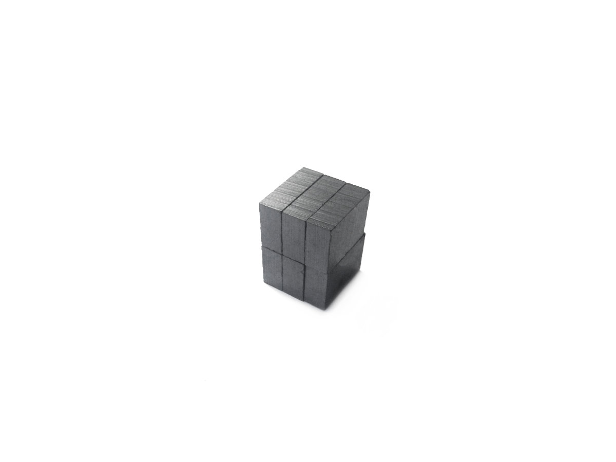 A small cube made of multiple stacked gray rectangular Hard Ferrite Magnets, arranged neatly against a plain white background. by Standex Detect