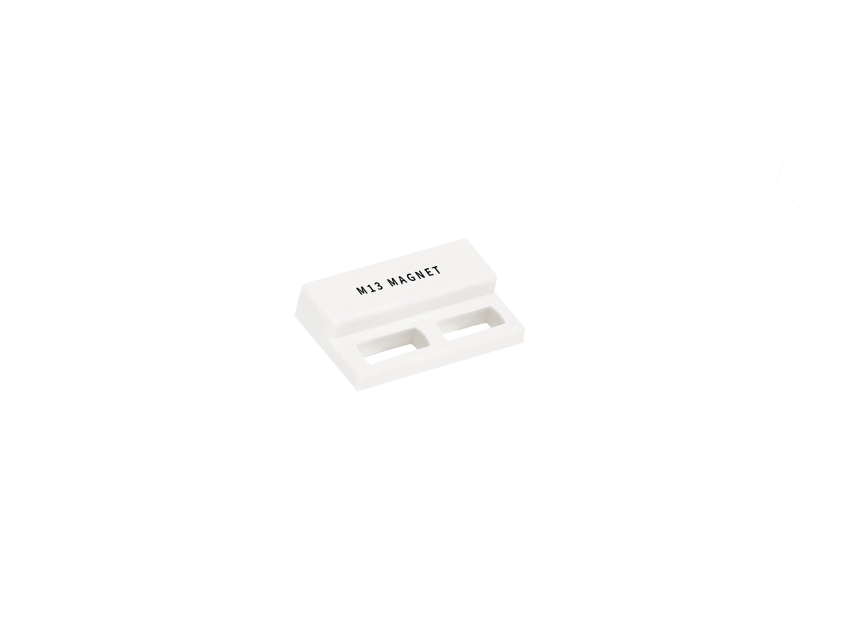 A small rectangular white plastic component labeled MJ1 MAGNET from the M13 Series Magnet line, featuring two rectangular slots on the bottom and isolated on a plain white background. by Standex Detect